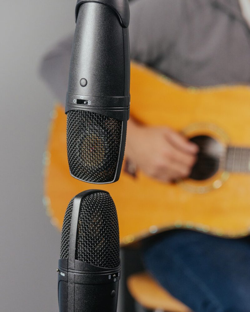 Close up of two microphones and an acoustic guitar